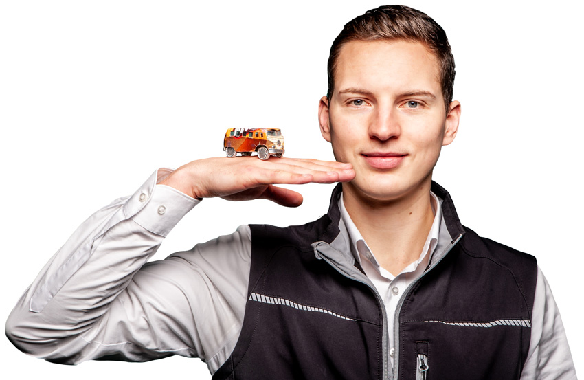 Sebastian Wyczisk in Arbeitsweste balanciert einen Modell-VW-Bus auf der Hand